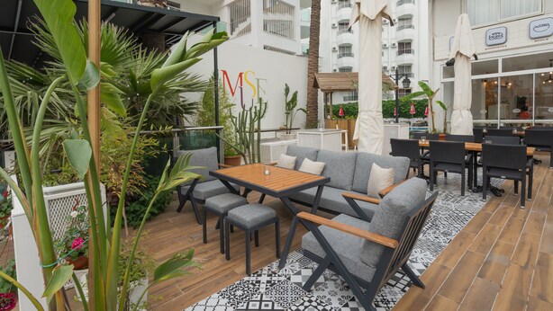 An outdoor patio area with seating, a wooden table, and potted plants. - Muse No:1 (Marmaris)