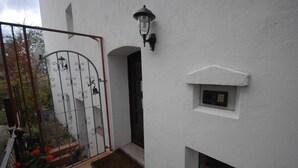 A white building with a metal gate, a small window, and a wall-mounted light fixture. - Airportgästehaus Bremen (Bremen)