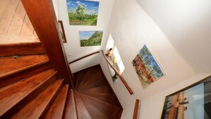 A wooden staircase with a handrail, white walls, and framed landscape paintings. - Airportgästehaus Bremen (Bremen)
