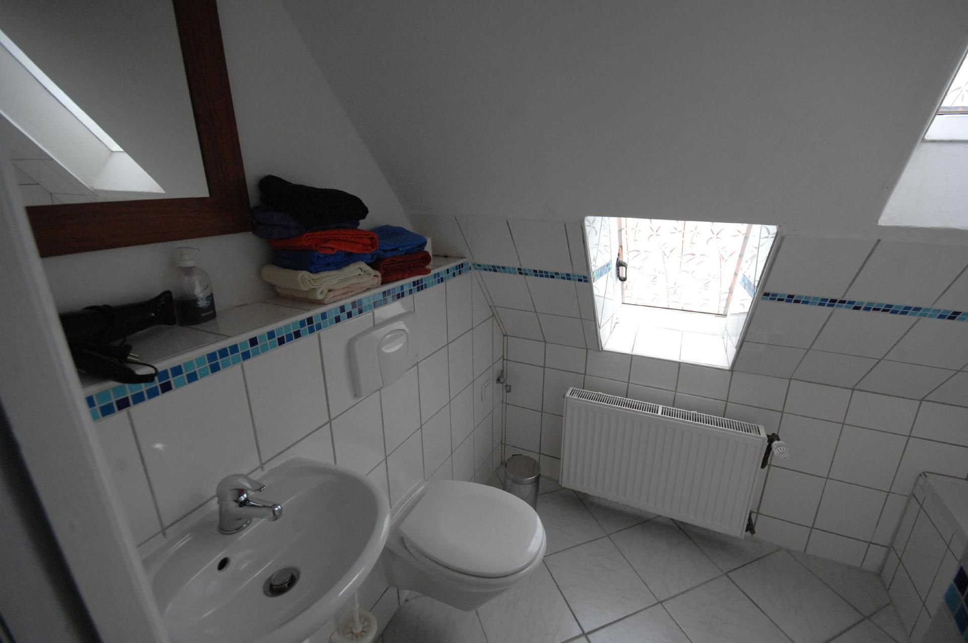 Un baño pequeño y sencillo con lavamanos, inodoro y ventana.