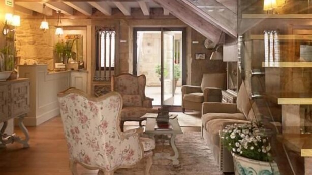 A spacious living area with a high ceiling, wooden beams, a staircase, and a view of the outdoors. - Hotel Real Cambados (Cambados)