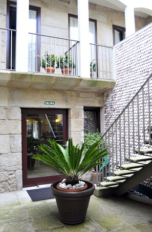 Un edificio con facciata in pietra, un balcone con piante in vaso e una scala con parete piastrellata.