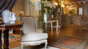 A spacious living room with a high ceiling, wooden beams, a large glass door leading to a dining area, and a plush white armchair. - Hotel Real Cambados (Cambados)