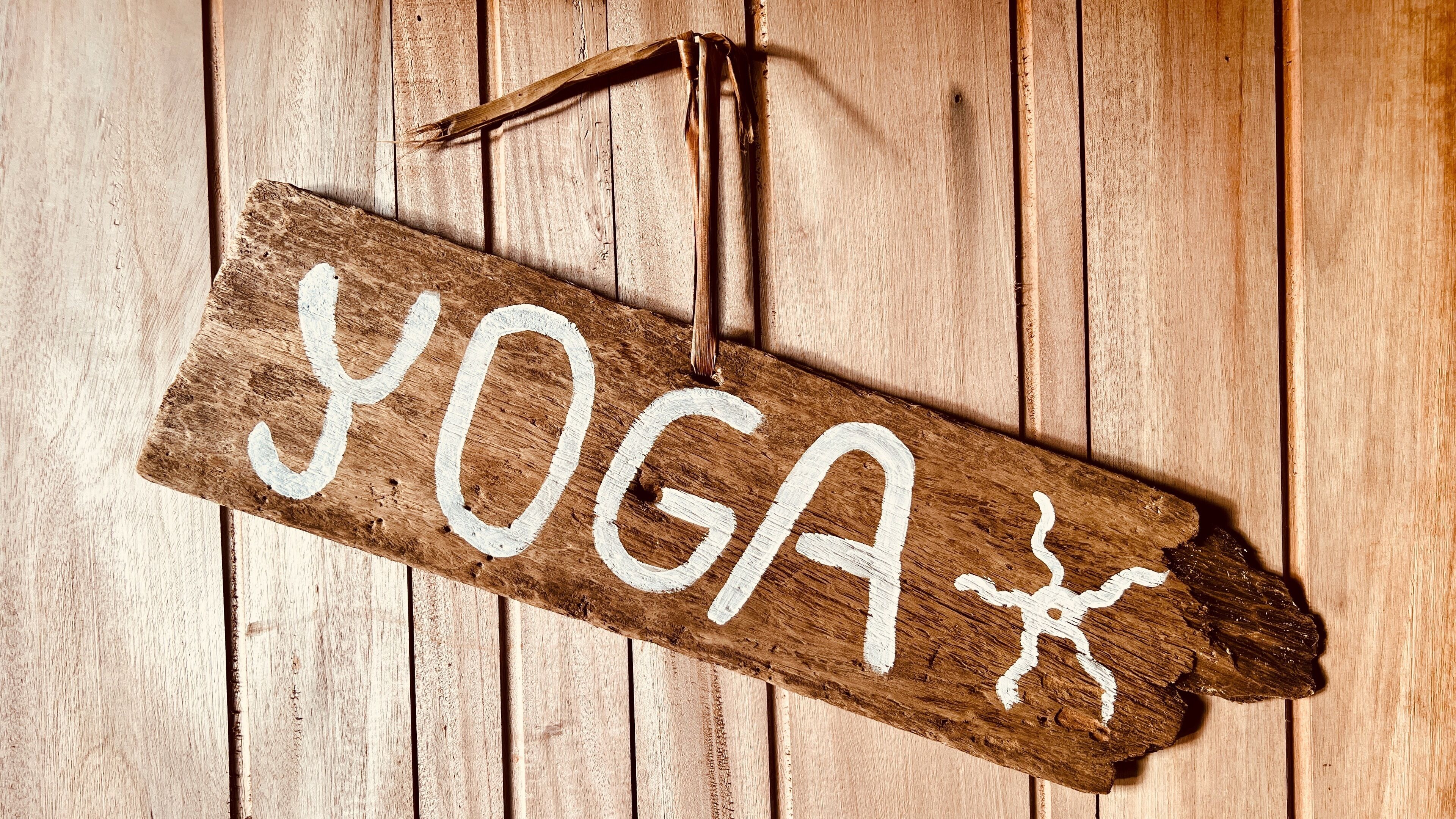 A wooden sign with the word "YOGA" and a yoga pose symbol.