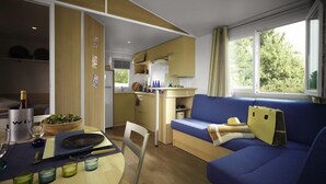 A compact living space with a kitchenette, a dining area, and a seating area with a sofa and a table. - Camping Le Diben (Larmor-Baden)