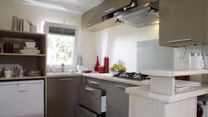 A modern kitchen with a built-in dishwasher, a stove, and a sink. - Camping Le Diben (Larmor-Baden)