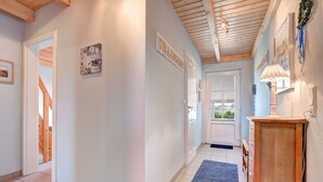 A hallway with a wooden ceiling, a blue rug, and a wooden cabinet with a lamp. - Ferienpark Am Meer Klipper (Butjadingen)