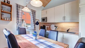 A dining area with a wooden table, blue and white checkered tablecloth, and four chairs. - Ferienpark Am Meer Klipper (Butjadingen)