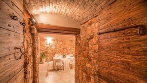 Un estrecho pasillo de paredes de piedra que conduce a un comedor con una mesa redonda para cuatro.