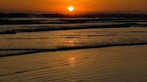 Un atardecer sobre una playa con olas.