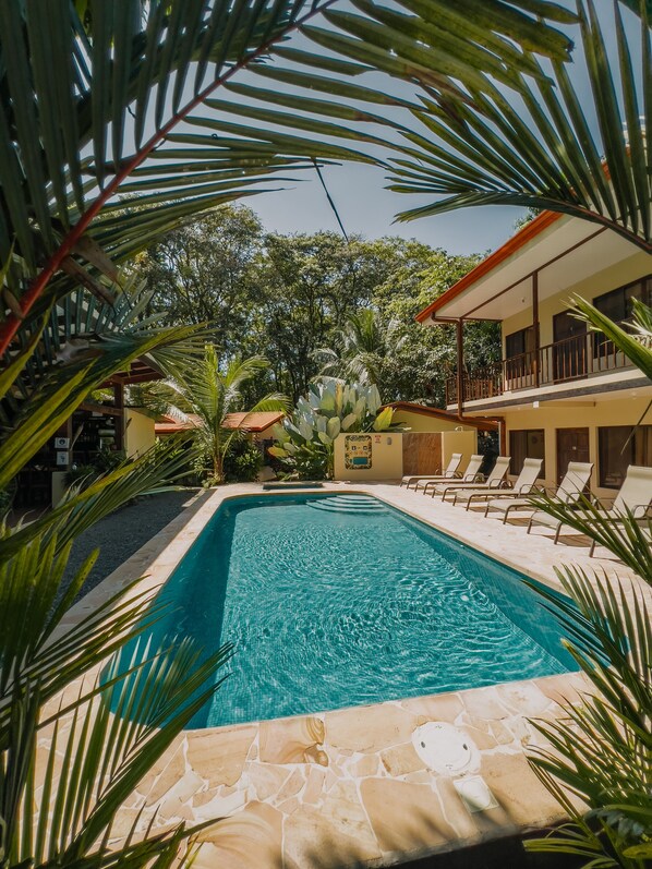 A swimming pool surrounded by palm trees and a building with a balcony. - Tropical Beach (Bahía Ballena)