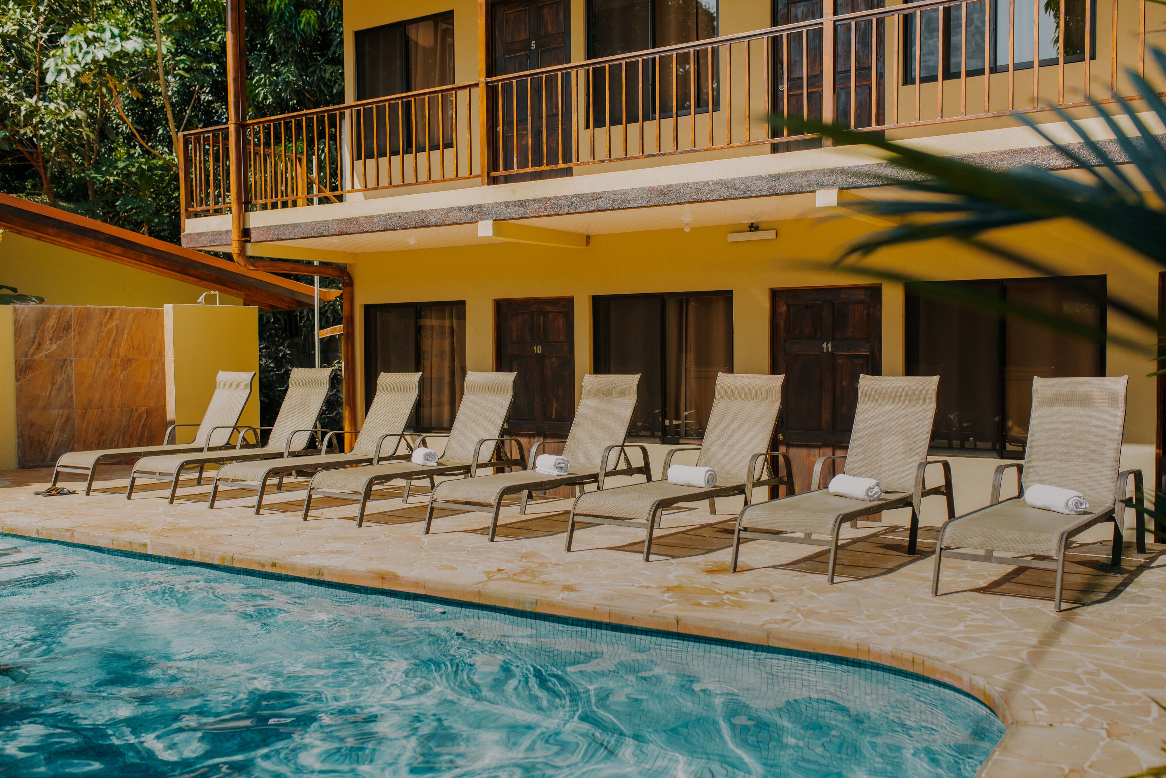 A pool area with lounge chairs and a building with multiple balconies.