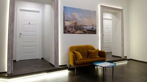 Un couloir avec un canapé, une petite table et un tableau encadré au mur.