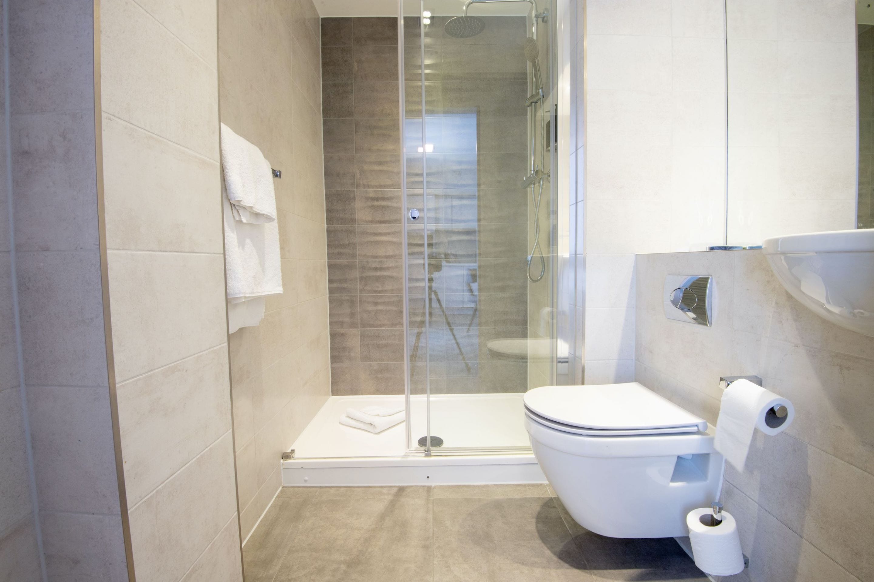 A modern bathroom with a glass-enclosed shower, a toilet, and a sink.
