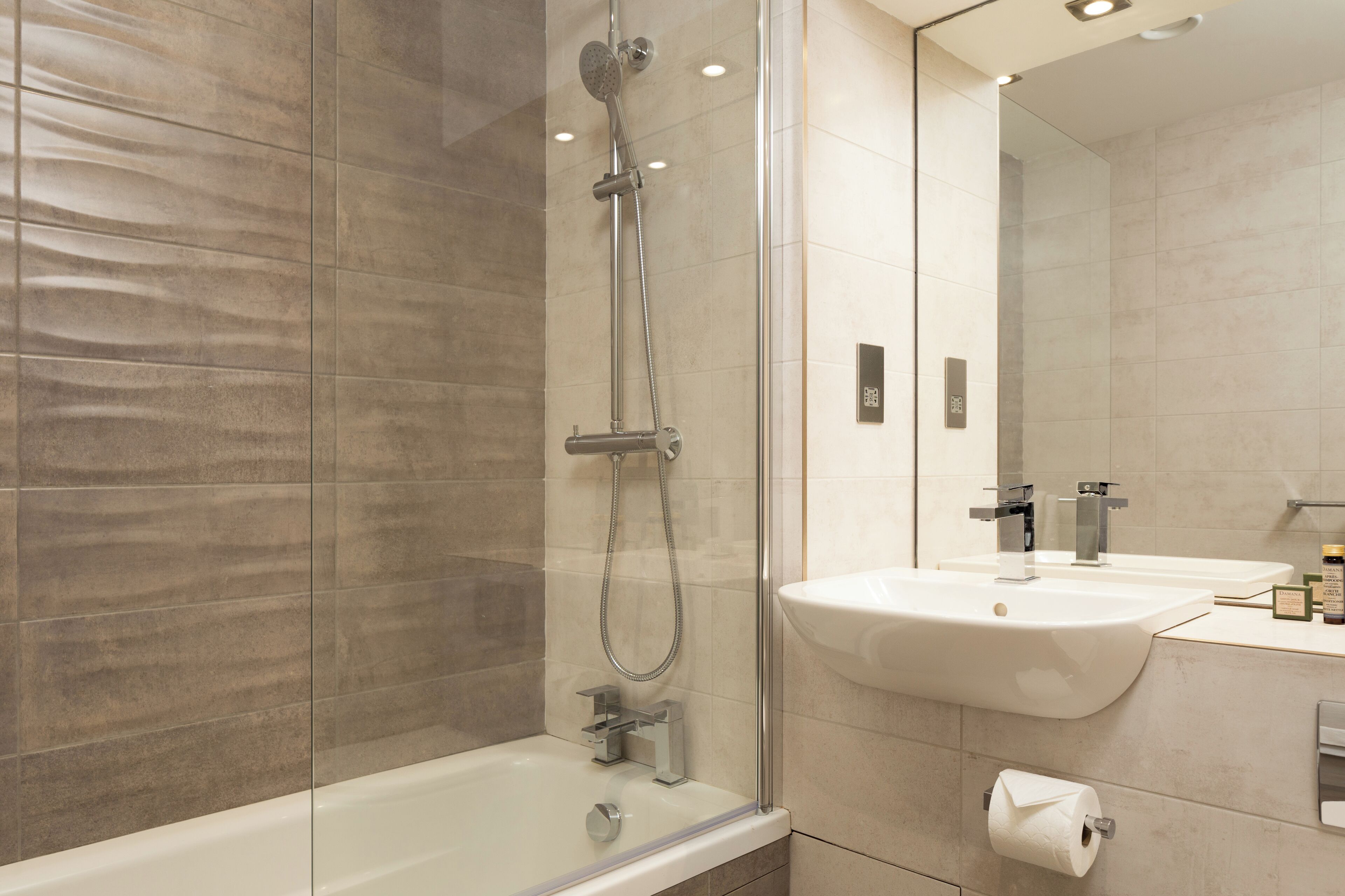 A modern bathroom with a glass-enclosed shower, a white sink, and a mirror.