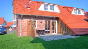 A two-story house with a red-tiled roof, a brick exterior, and a wooden door. - Ferienpark Am Meer Katamaran 1 (Butjadingen)