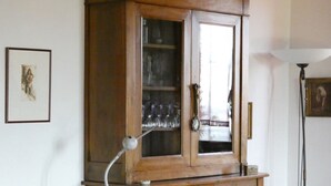 Un meuble en bois avec des portes en verre, une sculpture d’oiseau décorative et un tableau encadré accroché au mur.
