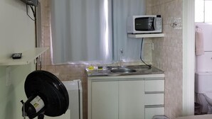 Una cocina compacta con microondas, lavabo y ventilador.