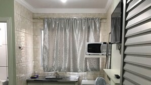 Una cocina compacta equipada con microondas, ventilador y refrigerador pequeño.