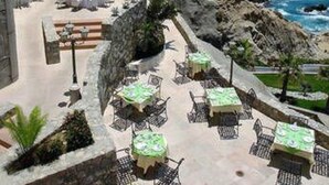 A coastal hotel with outdoor seating areas overlooking the sea, a pool, and a rocky shoreline. - Confortable Family Suite 2BD at Cabo San Lucas (Cabo San Lucas)