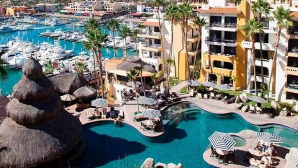 A resort with a central pool, multiple balconies, and a marina in the background. - Fancy and Enjoyable Studio in Cabo San Lucas (Cabo San Lucas)