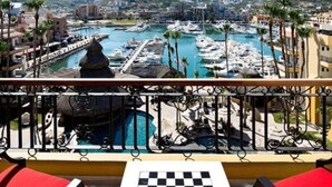 A balcony with a chessboard, overlooking a marina with boats and a cityscape. - Fancy and Enjoyable Studio in Cabo San Lucas (Cabo San Lucas)