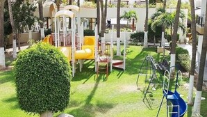 A children's play area with slides and swings, surrounded by well-maintained grass and trees. - Fancy and Enjoyable Studio in Cabo San Lucas (Cabo San Lucas)