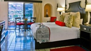 A hotel room with a bed, a desk, and a chair. There is a view of a city through a large window. - Fancy and Enjoyable Studio in Cabo San Lucas (Cabo San Lucas)