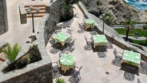 Eine Terrasse am Meer mit Tischen und Stühlen, mit Blick auf den Ozean.