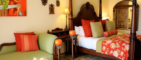 Una habitación tradicional con cama, sofá verde, mesita de noche y lámpara.