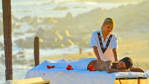 A massage therapy session on a beach with a person lying on a massage table, another person attending to them, and cacti in the background. - Hacienda Residences, Private 3-bedroom Villa (Cabo San Lucas)