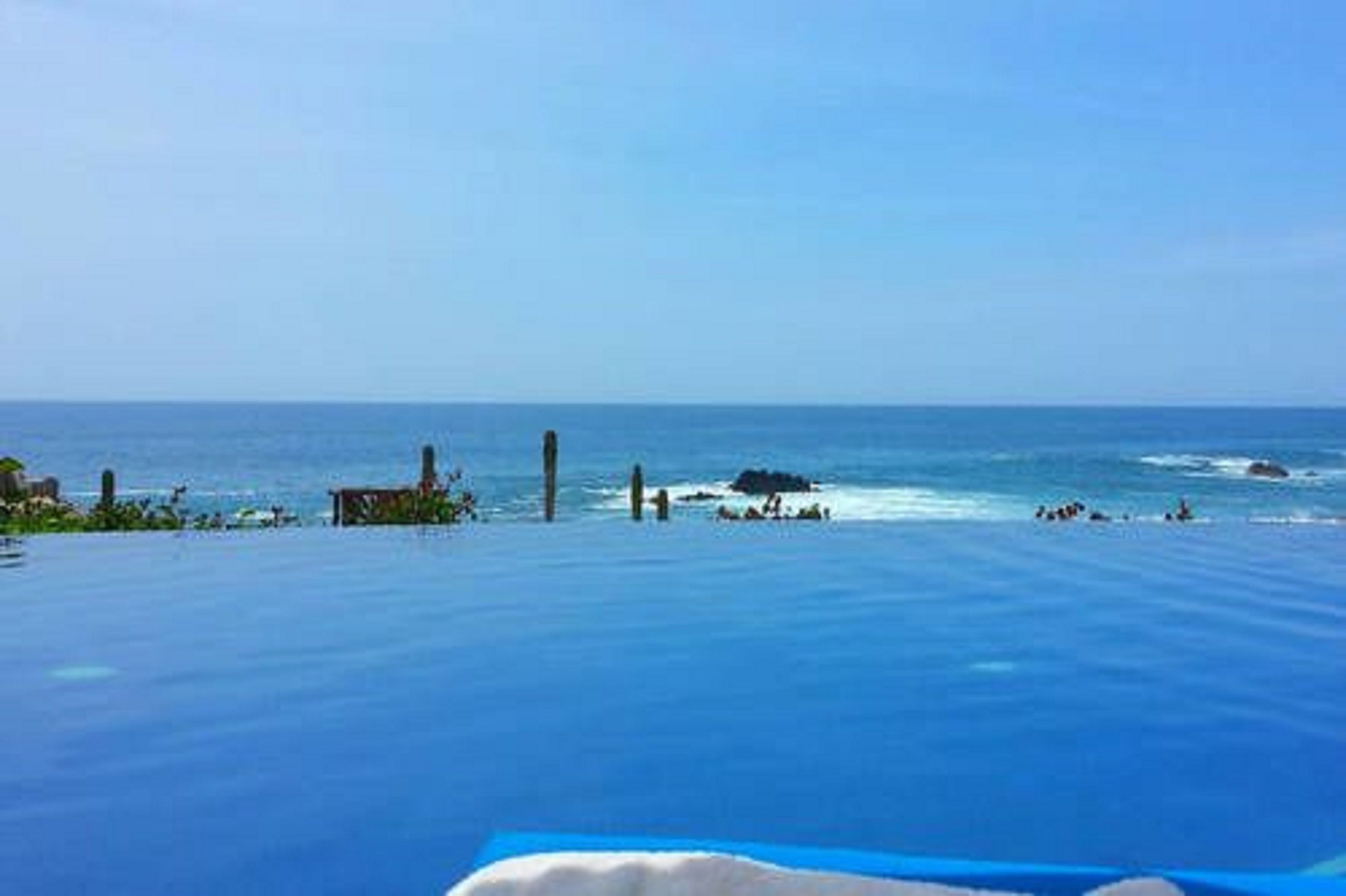 Una vista despejada del océano, una playa arenosa y algo de vegetación.