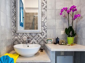 A bathroom with a large white sink, a mirror, a green potted plant, and a tiled backsplash. - Zidanos Luxurious Villa (Lefkada)