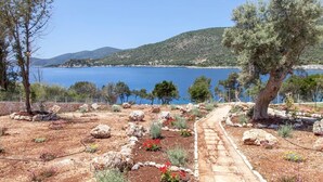A coastal landscape with a stone pathway leading to a view of the sea and hills. - Zidanos Luxurious Villa (Lefkada)