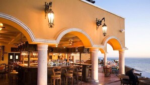 Un espace bar extérieur avec des sièges, un comptoir et une vue sur la mer.
