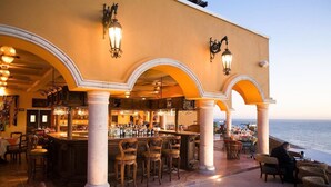 An outdoor bar area with a view of the sea, featuring a bar counter, seating, and decorative lighting. - Rated for the Best Value in Cabo San Lucas!! 2BR 8P (Cabo San Lucas)