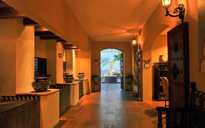 A hallway with a statue at the end, leading to a view of the sea.