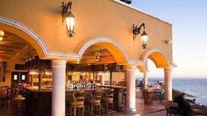 Zona de bar con vista al mar, que incluye barra, asientos e iluminación decorativa.