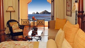 Habitación de hotel con cama, sofá, mesa de comedor y vista al mar.