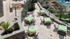 A seaside patio with tables and chairs, overlooking the ocean. - Unique Master 1 Bedroom Suite 1 King (Cabo San Lucas)