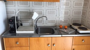 Una cocina con cafetera, lavabo, estufa y un tendedero.
