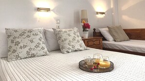Habitación de hotel con cama, dos mesitas de noche, una bandeja con bebidas y lámparas de pared.