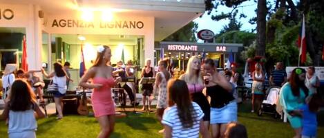 An outdoor event with people dancing and a restaurant/bar in the background.