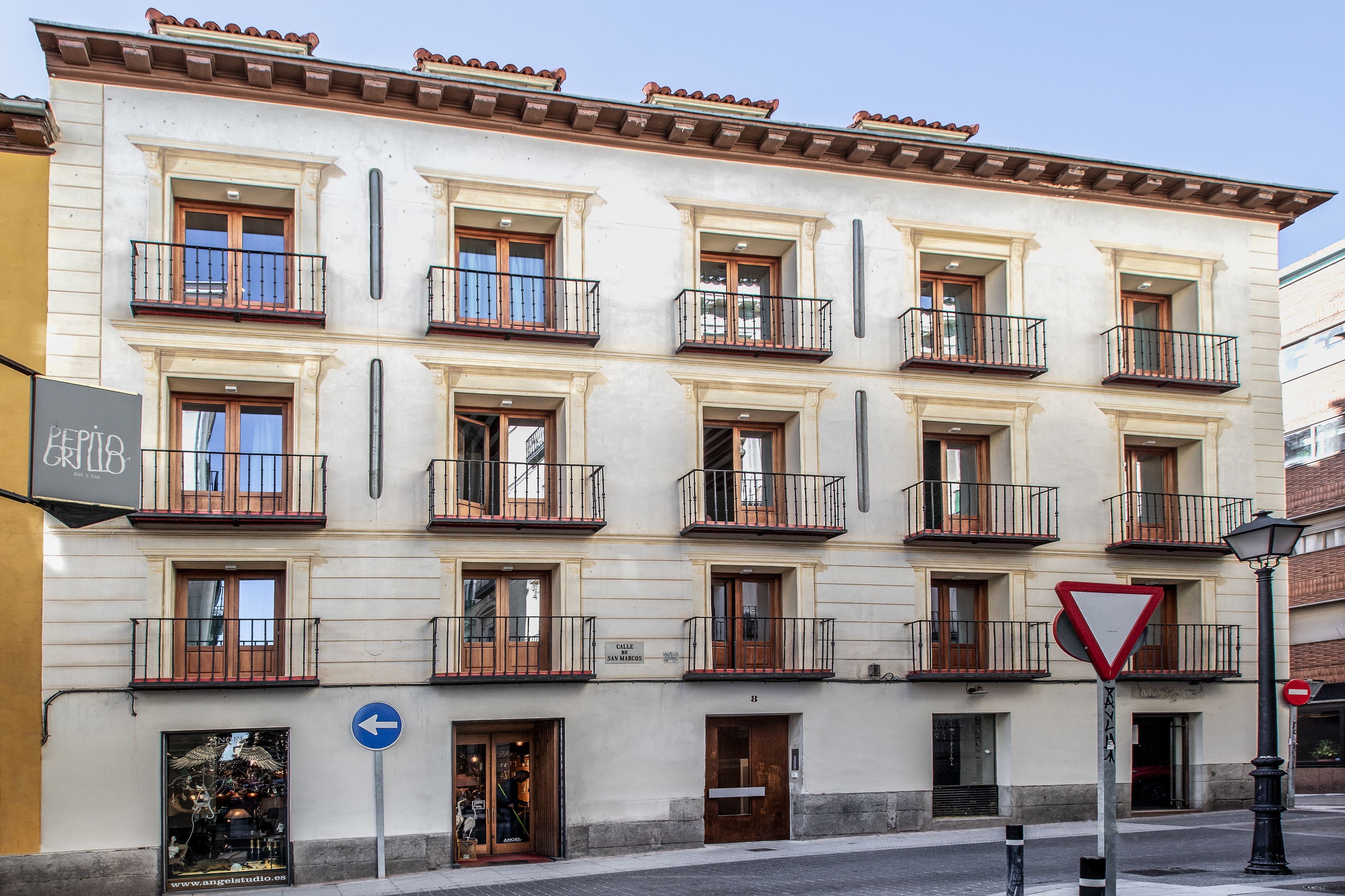 A multi-story building with balconies, a 'No Entry' sign, and a directional sign.