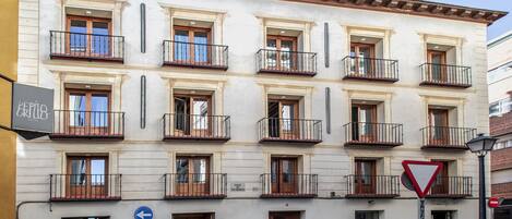 Un edificio de varios pisos con balcones, un letrero de 'Prohibido el paso' y una señal de indicaciones.