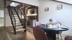 Un comedor con una mesa redonda, sillas estampadas y una escalera que sube a un nivel superior.