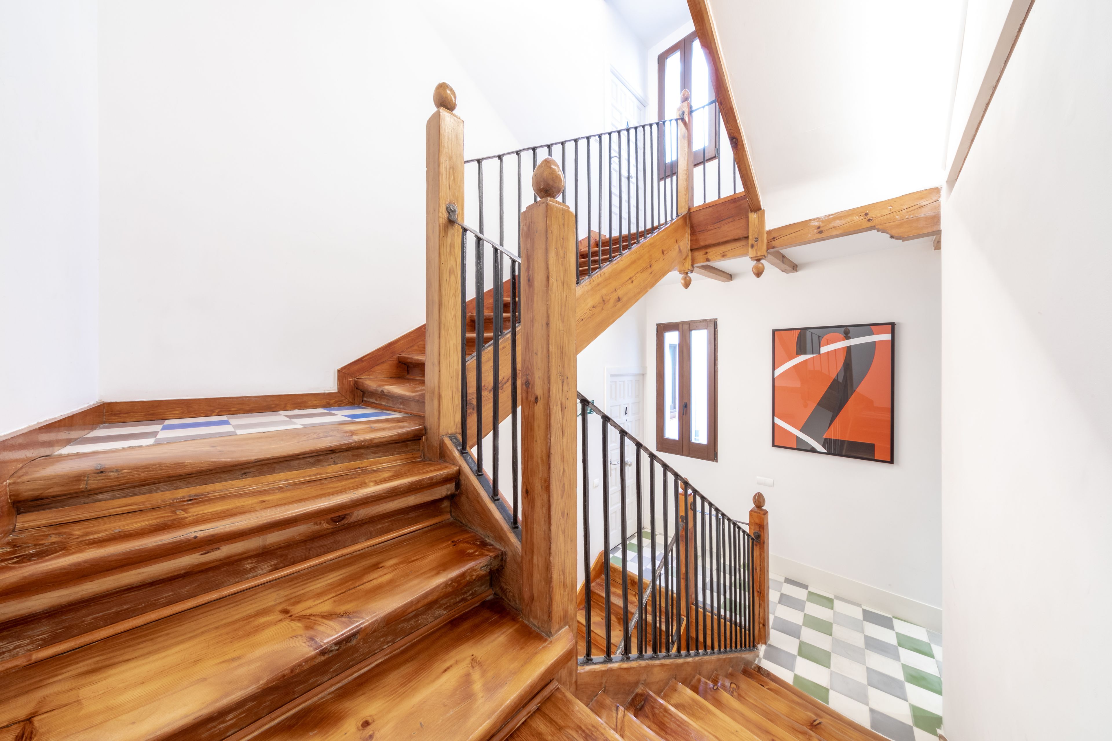 A wooden staircase with a black railing, leading to an upper floor.