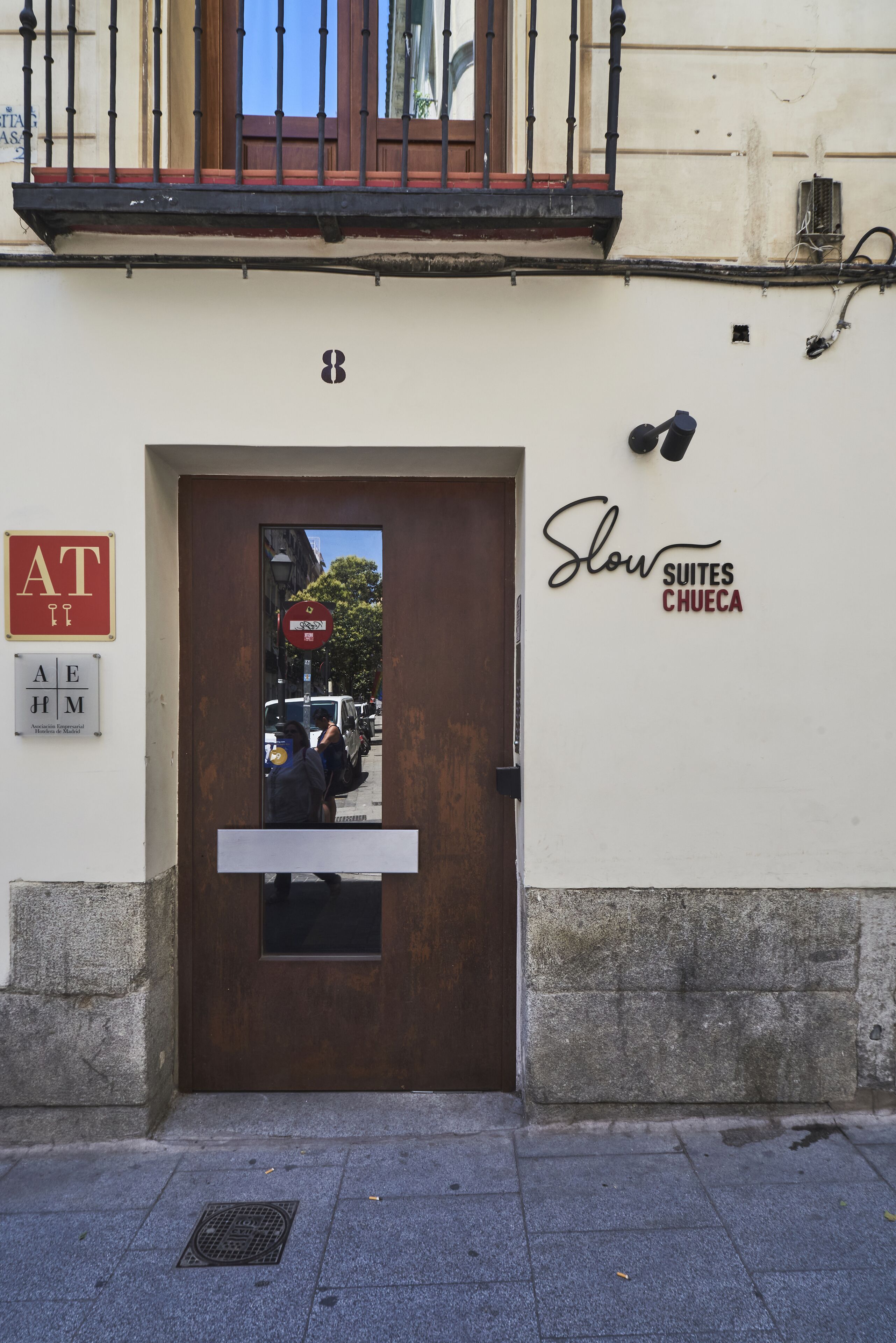 A hotel entrance with a brown door, a sign for AT, and a sign for Slow Suites Chueca.