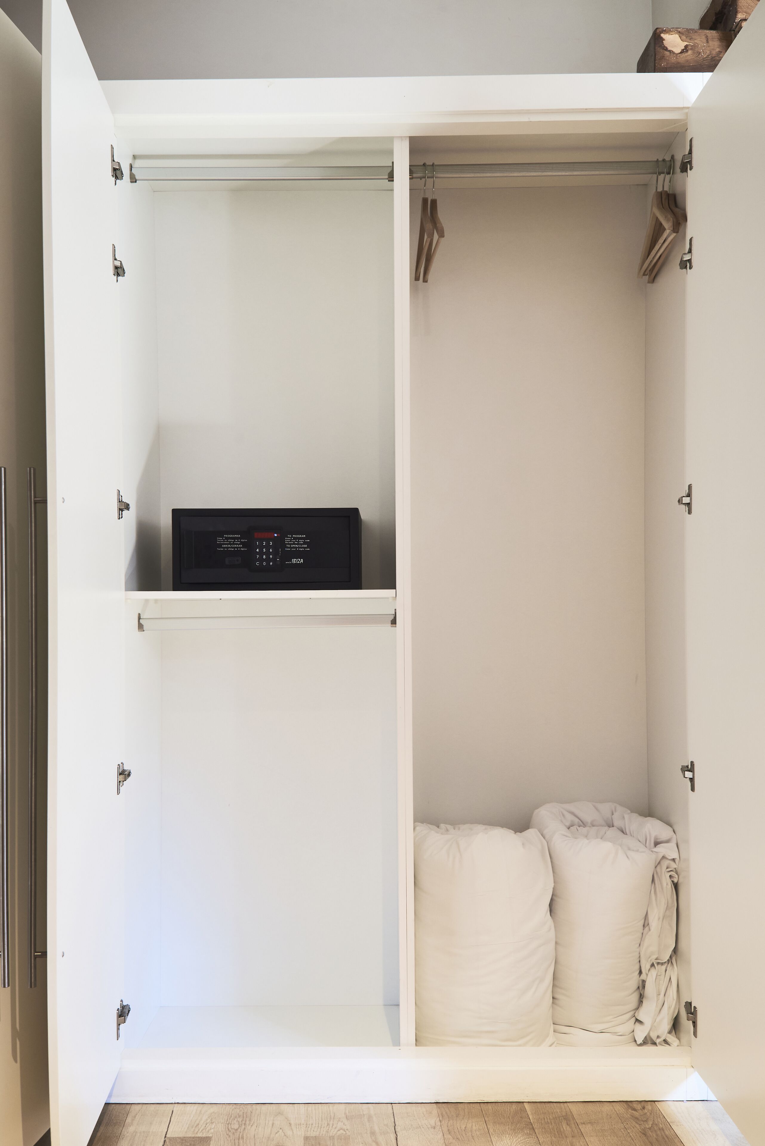 A white wardrobe with a microwave on the top shelf and a folded blanket in the bottom drawer.