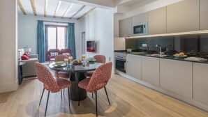Una cocina moderna con microondas, horno y un comedor con una mesa redonda y sillas estampadas.
